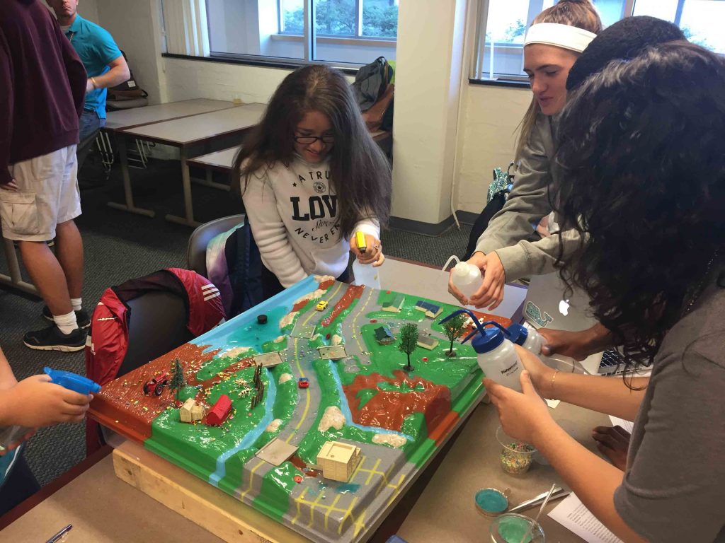 Lafayette College and Cheston Elementary students squirt liquid on the pollution model from bottles.