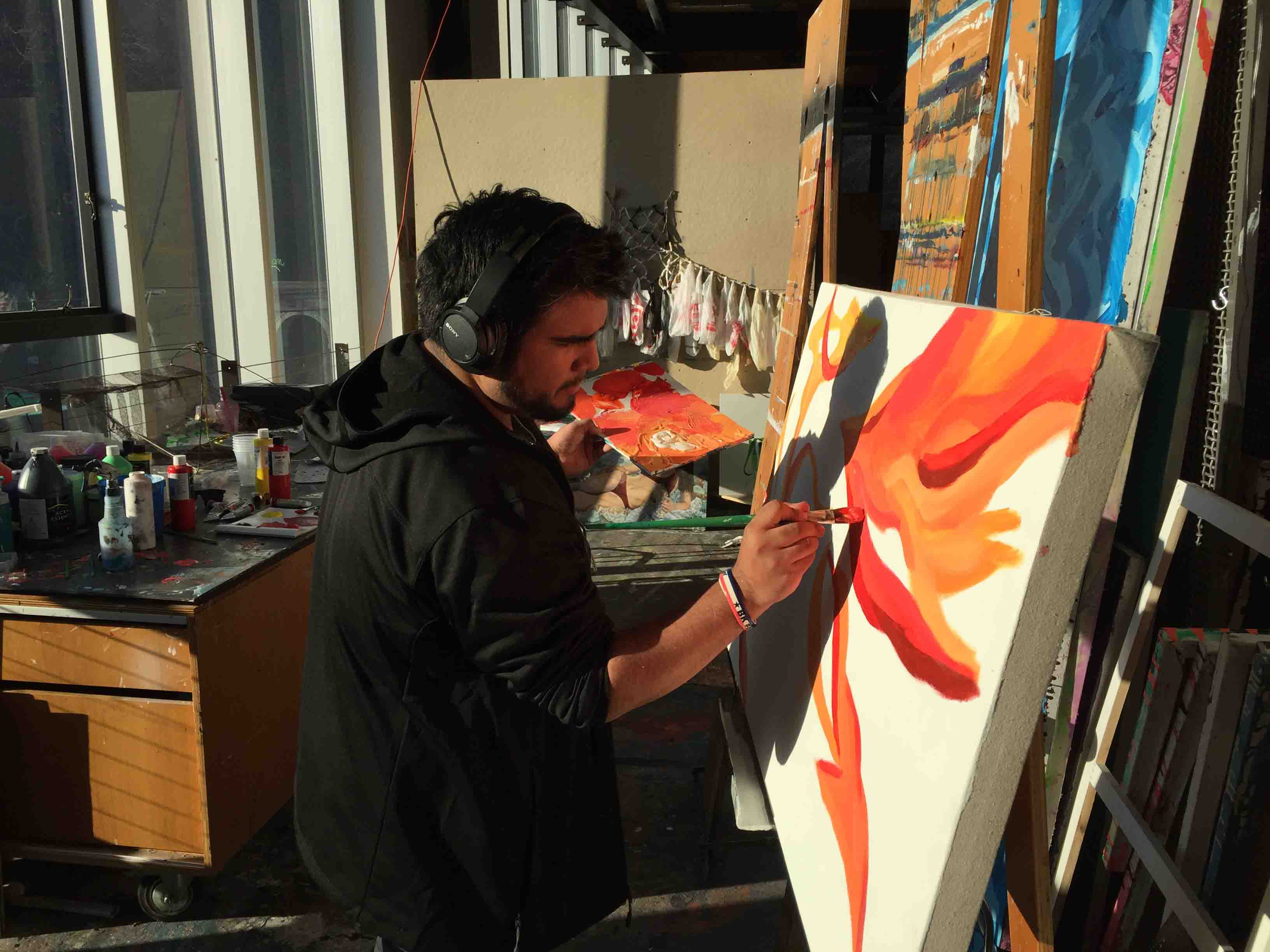 Pablo Pollish '18 paints on canvas in the Williams Visual Arts Building.