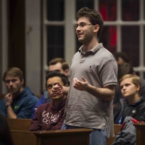A male student stands and speaks from the audience at the Keith Whittington lecture.