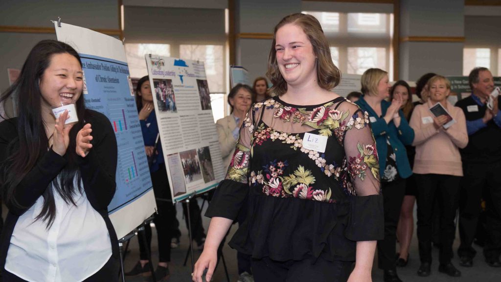 Elizabeth Rohricht '21 smiles and walks forward to receive her award at the 9th annual Center for Community Engagement Expo.