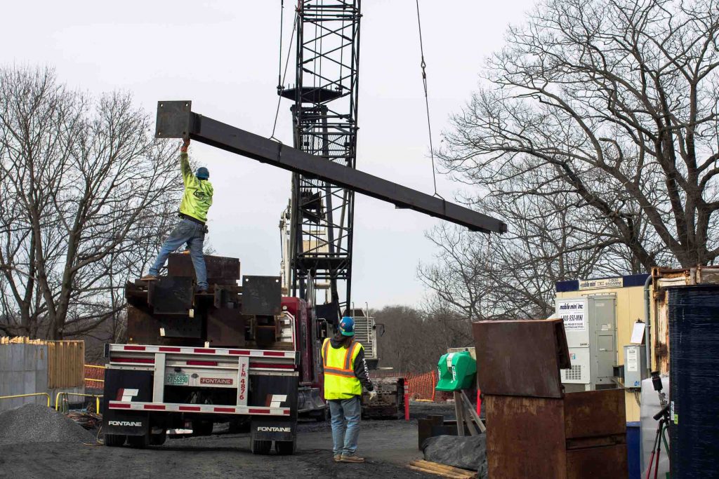 Workers bring in a beam through a crane at the site of Rockwell Integrated Sciences Center.
