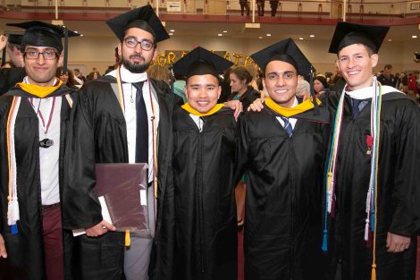 Five men graduates pose for a photo after Commencement.