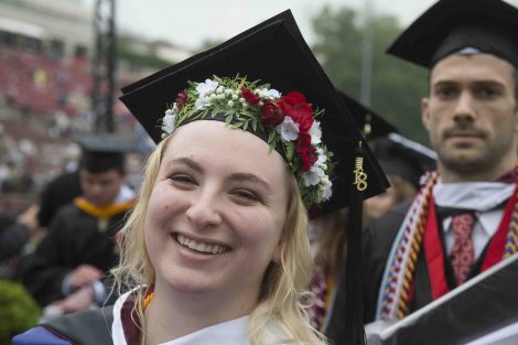 A grad with flowers around her head smiles after Commencement.
