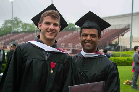 Two graduates pose for a photo after Commencement.