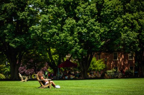 A student sits in an Adirondack chair on the Quad.