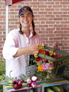 A student carries a basket of flowers from LaFarm.