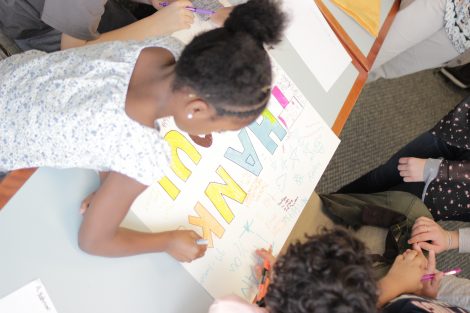 Local third-graders use markers to create letters on a poster during a class taught by Lafayette College students in the Happiness First-Year Seminar.