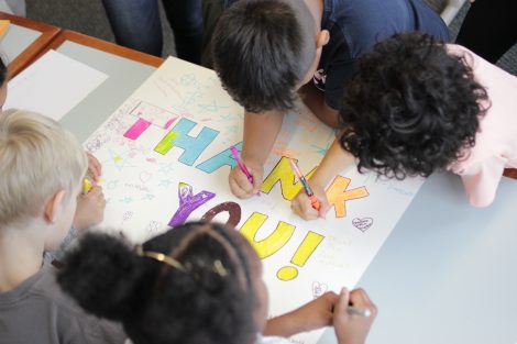 Local third-graders use markers to create letters on a poster during a class taught by Lafayette College students in the Happiness First-Year Seminar.