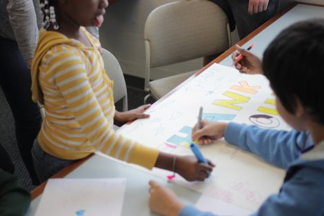 Local third-graders use markers to create letters on a poster during a class taught by Lafayette College students in the Happiness First-Year Seminar.