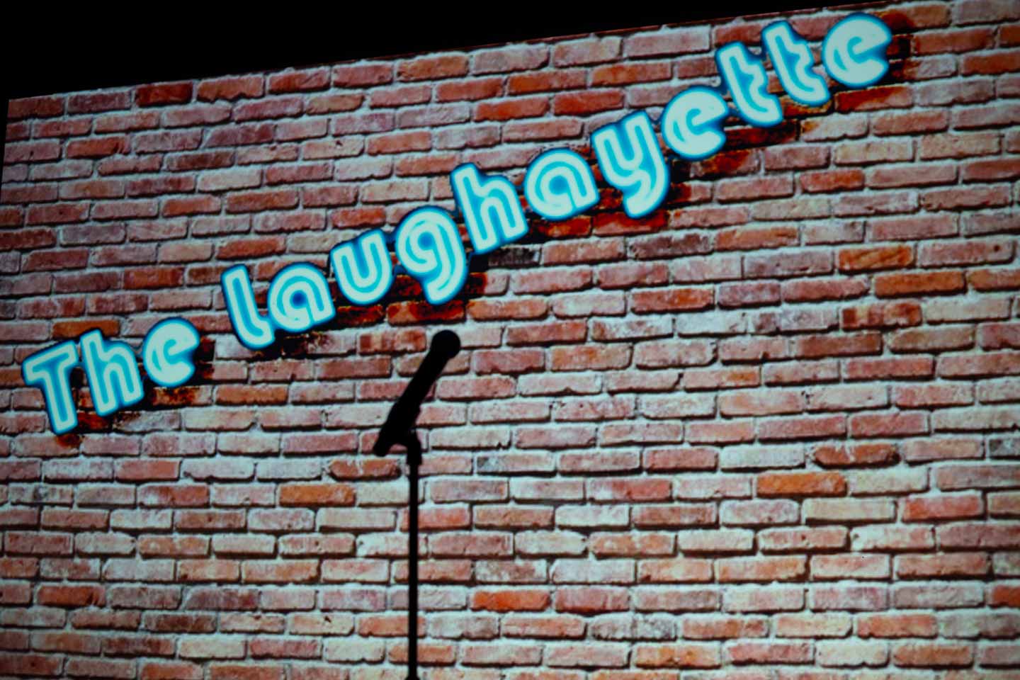 A projection on a brick wall says "The Laughayette."