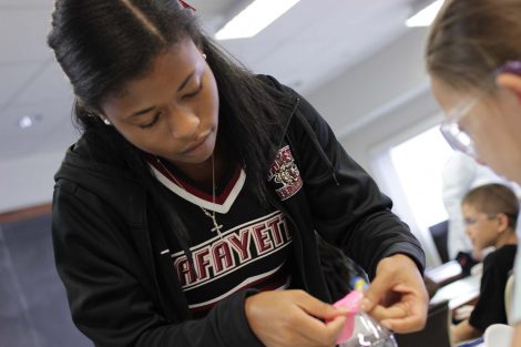 Lafayette student helps secure a balloon on to a bottle.