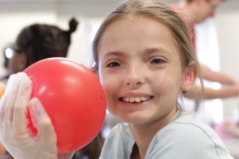 Girl smiles with red balloon.