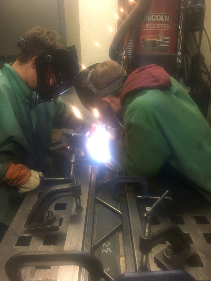 Two students perform welding on the model steel bridge.