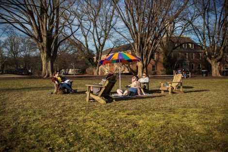 students sit in chairs with a beach umbrella