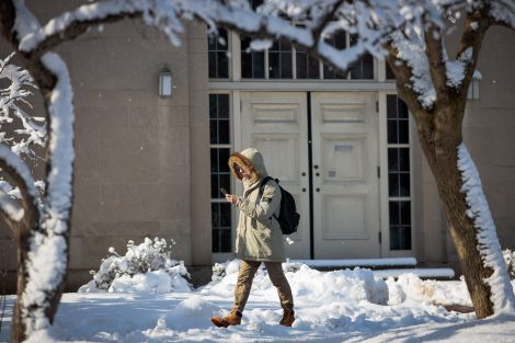 A student looks at her smartphone as she walks by Colton Chapel after snowfall.