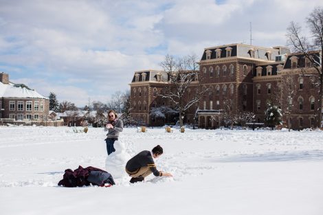 Two students make a snowman on the Quad.
