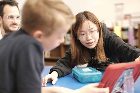 A Lafayette student helps a third grader with a code project.