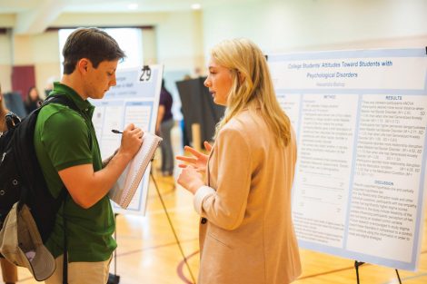 Students explain their research to visitors at the 2019 spring poster session in Kamine Gymnasium in Kirby Sports Center.