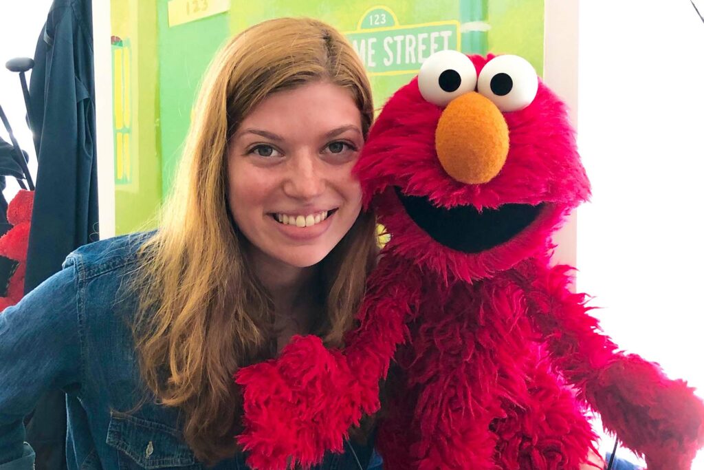 Student poses cheek to cheek with Elmo, the muppet