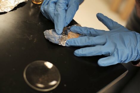 High school student Trisha Pakkala scrapes dried solution off of foil.