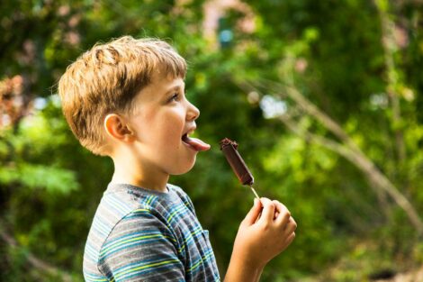 A boy sticks out his tongue daring himself to eat the ants on his ice cream