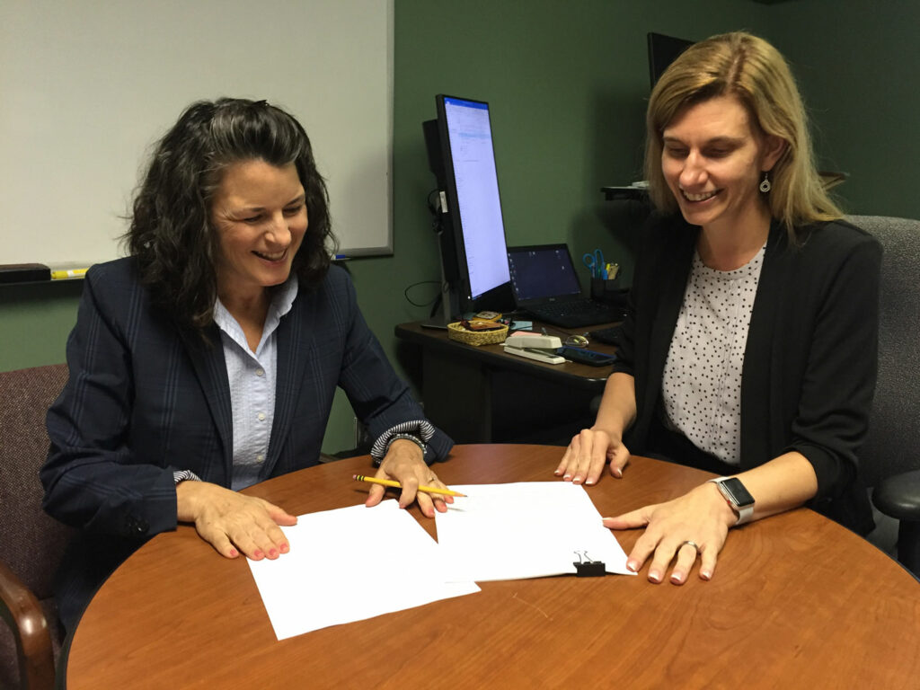 Economics professors Susan Averett and Julie Smith look at an academic paper on a table.