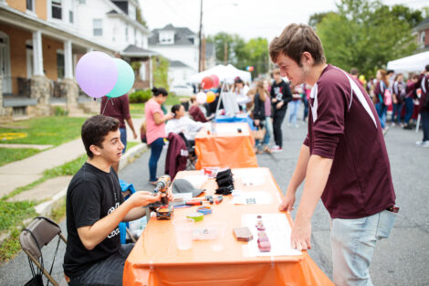 a student looks at dan goodman's exquisite handmade rings at block party