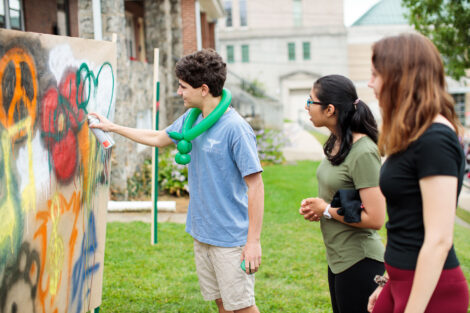 students legally apply graffiti to a sign at block party