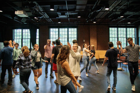 Several pairs of students give each other high-fives during a workshop led by Improvised Shakespeare Company.