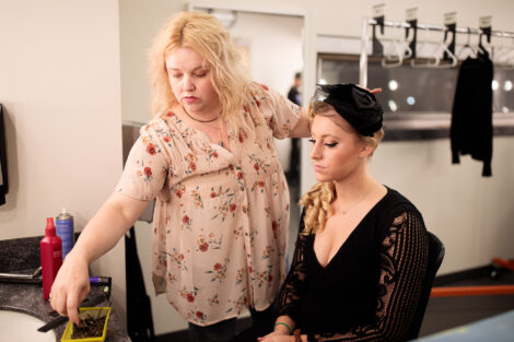 students prepare hair and makeup backstage