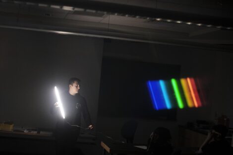 Lafayette student holds another bulb and the spectrum of light appears through the glasses