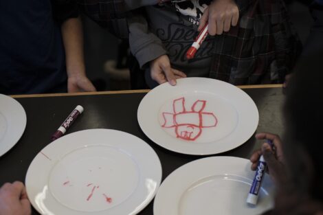 Student makes his drawing move as water lifts up the whiteboard marker from the surface of the plate