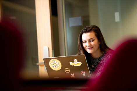 A student looks at her laptop and smiles on the first day of spring semester.