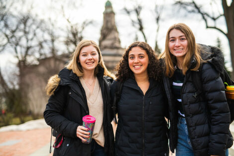 Three friends pose for a photo together on the Quad on the first day of spring semester.