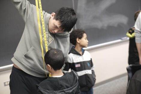 Lafayette student uses tape measure to measure height of student