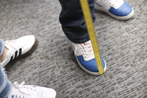 The bottom of the tape measure is held beneath the foot