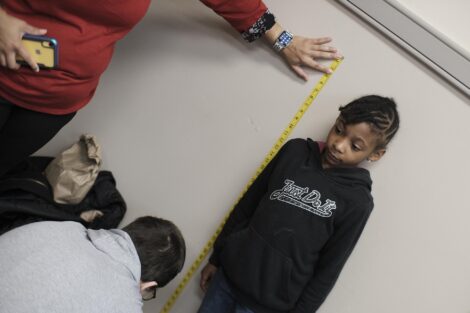 Elementary student stands against the wall to be measured