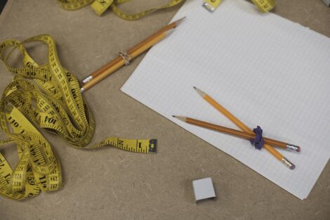 Tape measures, pencils, and paper sit on a desk