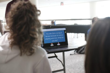 Students discuss a prompt about friendship that is on a computer screen