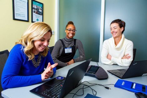 Student extern smiles while working with two people at Olympus