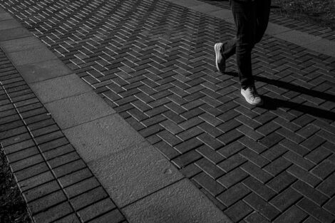 Black and white image of a student's feet as they rush to class across the quad,