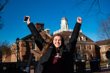 A student on the Quad showing her love for warm winter days. Kirby House in the background.