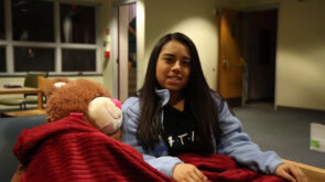Flor Caceres '22 sits next to a teddy bear.