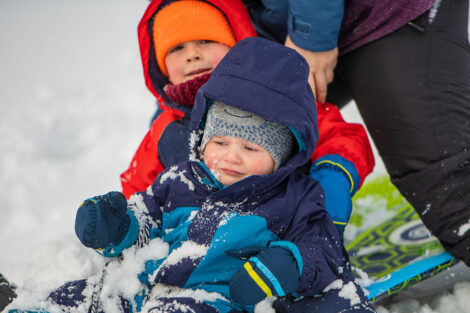 two young children bundled up in snow gear on a sled