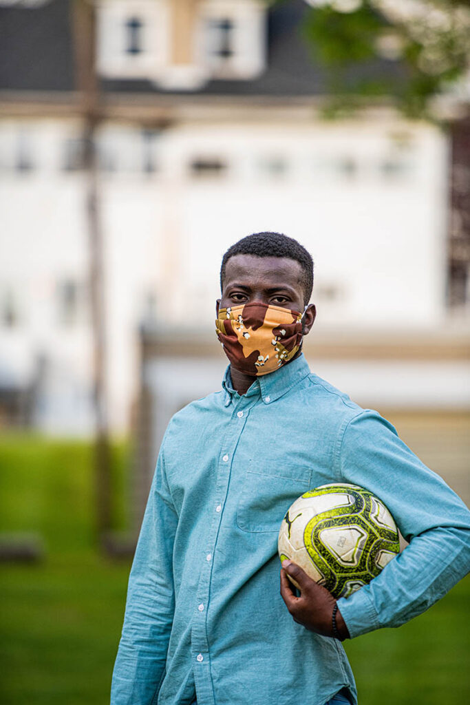 Basit Balogun '21, masked with a soccer ball in his left hand