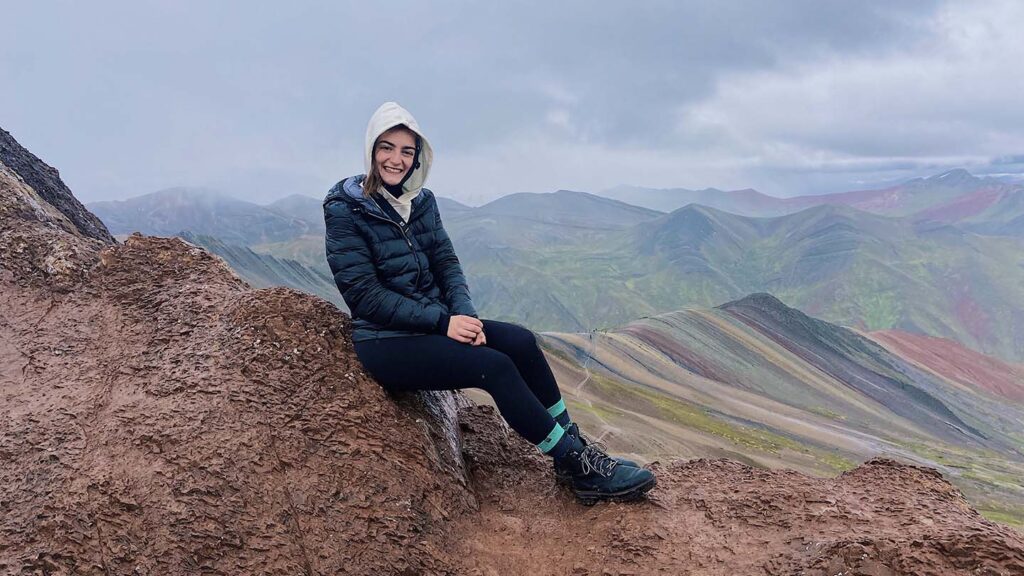 Victoria Puglia ’21 sits on top of rocks with mountains in the background in Peru