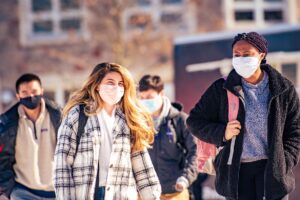 Masked students walk in front of Farinon College Center