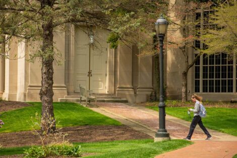 A student wearing a mask walks in front of Colton Chapel.