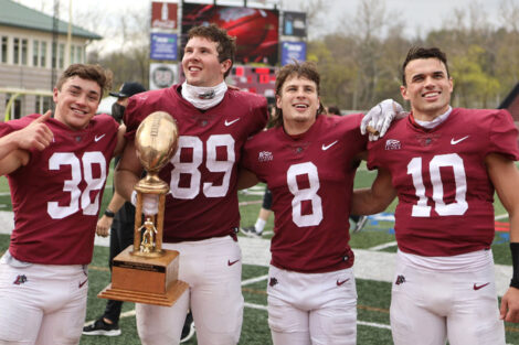 Lafayette College football players hold a trophy and smile after winning the 156 Rivalry game against Lehigh