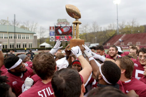 Lafayette College football players hold a trophy and smile after winning the 156 Rivalry game against Lehigh
